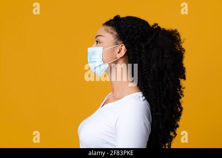 Concetto di protezione dai virus. Vista laterale della donna nera in maschera medica protettiva Foto Stock