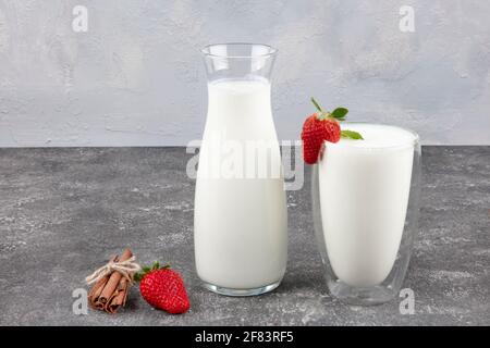 Yogurt sano biologico bevibile Kefir in un bicchiere. Primo piano su un bicchiere pieno di Kefir bianco arricchito con alcune foglie di menta. Foto Stock