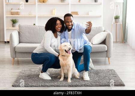 Giovane coppia nera che prende selfie con il cane a casa Foto Stock