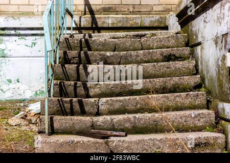 Vecchia scala spezzata. Scalini in cemento rotti in una casa abbandonata. Foto Stock