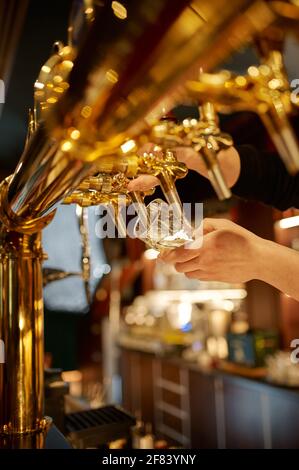 Il barman versa la birra fresca in un bicchiere Foto Stock