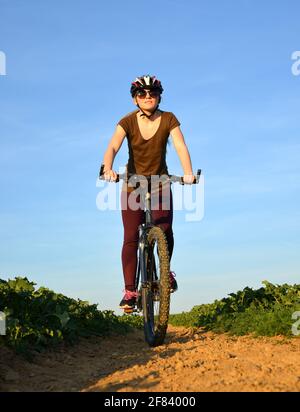 Ragazza che guida una bicicletta su una strada sterrata. Foto Stock