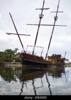 barca abbandonata su acqua still sotto le nuvole pesanti in estate Foto Stock