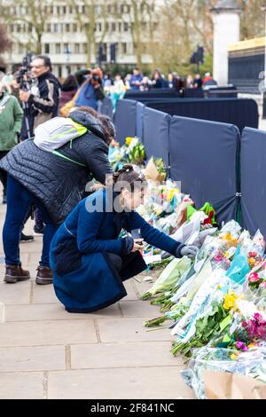 11 aprile 2021, Londra, Regno Unito - Donna che getta fiori come tributo al principe Filippo, duca di Edimburgo fuori di Buckingham Palace dopo la sua morte il 9 aprile Foto Stock