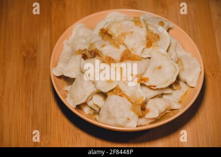 Gnocchi in ciotola con cipolle fritte. Gnocchi, ripieni di purè di patate serviti con cipolla fritta Foto Stock