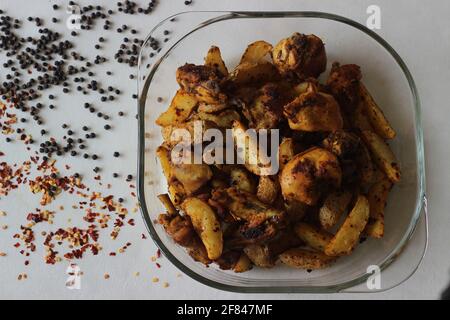 Frittura di pollo secca e spicchi di patate, fritti all'aria. Scatto su sfondo bianco Foto Stock