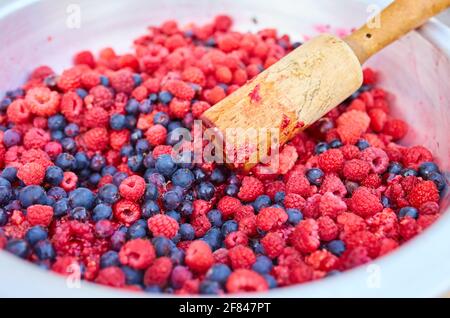 Lamponi e ribes nero in una ciotola con un pestello, facendo marmellata fatta in casa Foto Stock