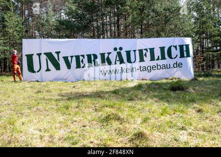 Schleife, Germania. 11 Apr 2021. Un banner con l'iscrizione 'UNVERKÄUFLICH www.kein-tagebau.de' è allestito nella foresta vicino a Schleife. L'azione di protesta 'Unverkäuflich' della rete ambientale di Grüne Liga a Schleife, nei pressi della miniera d'opencast Nochten, nel distretto di Görlitz, è diretta contro la minaccia del dragaggio di LEAG (Lausitz Energie Bergbau AG). Credit: Daniel Schäfer/dpa-Zentralbild/dpa/Alamy Live News Foto Stock