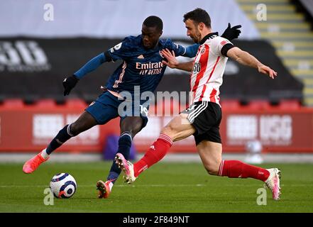 Nicolas Pepe di Arsenal (a sinistra) e Enda Stevens di Sheffield United combattono per la palla durante la partita della Premier League a Bramall Lane, Sheffield. Data immagine: Domenica 11 aprile 2021. Foto Stock