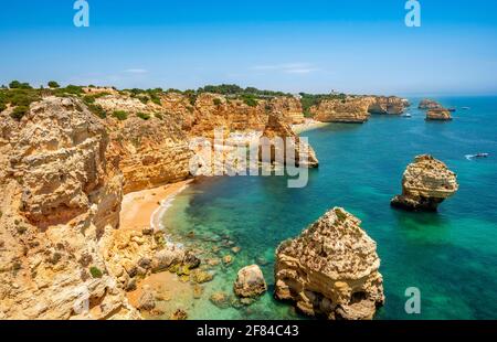 Vista su scogliere di rocce arenaria scoscese, formazioni rocciose nel mare turchese, spiaggia sabbiosa sulla scogliera, Praia da Marinha, Algarve, Lagos, Portogallo Foto Stock