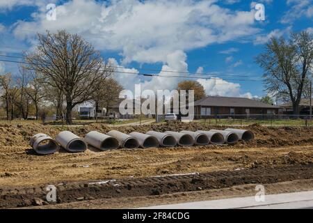 Pile di tubi di scarico di calcestruzzo sul terreno preparano per installazione sotterranea la vista della strada di costruzione posto in blu sfondo del cielo Foto Stock