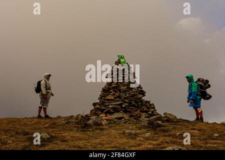 Turisti in impermeabile si trovano sulla cima della montagna, Monte Brebeneskul e nebbia, nuvole di pioggia sulla dorsale montenegrina, turisti felici.2020 Foto Stock