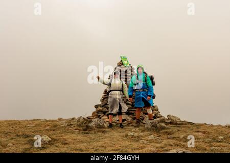 Turisti in impermeabile si trovano sulla cima della montagna, Monte Brebeneskul e nebbia, nuvole di pioggia sulla dorsale montenegrina, turisti felici.2020 Foto Stock