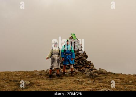 Turisti in impermeabile si trovano sulla cima della montagna, Monte Brebeneskul e nebbia, nuvole di pioggia sulla dorsale montenegrina, turisti felici.2020 Foto Stock