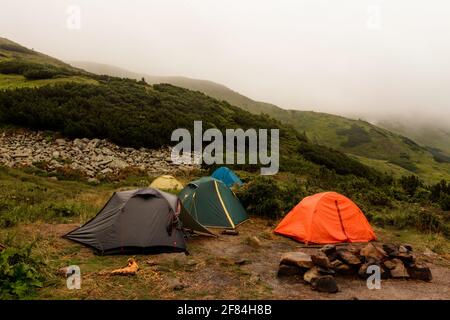 Una piccola città tenda in montagna, tende sul lago in montagna, la zona vicino al lago Brebeneskul, i monti Carpazi, nebbia e pioggia in Foto Stock