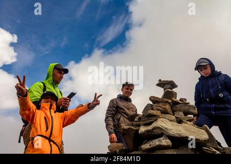 Un gruppo di turisti si trova sulla cima della montagna in abbigliamento sportivo, la cresta montenegrina e la cima del Monte Rebra.2020 Foto Stock