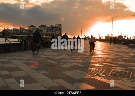 Weston Super Mare, Regno Unito. 11 Apr 2021. In una fredda serata ciclisti sono visti sulla passeggiata come il tramonto su Weston Super Mare, Somerset Nord. Credit: Robert Timoney/Alamy Live News Foto Stock