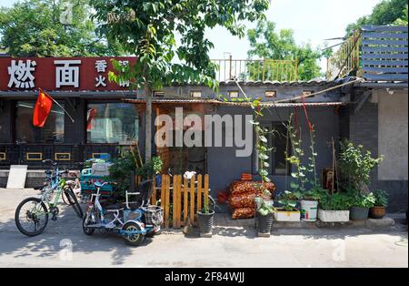 Giardino frontale di una casa in un vicolo hutong nel centro di Pechino, Cina, con noodle bar accanto Foto Stock