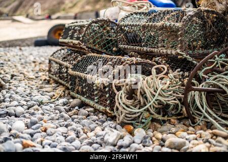 Attrezzatura da pesca del granchio lasciata sulla spiaggia di Cromer che comprende pentole da pesca, corda, ancoraggio in metallo e parafanghi. Profondità di campo poco profonda, messa a fuoco selettiva e bokeh Foto Stock