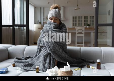 Donna malata seduta in cappuccio coperta di plaid che prende la medicina Foto Stock