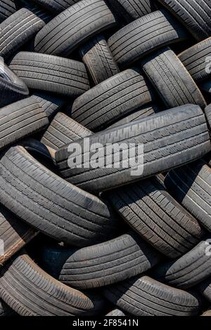 Molti pneumatici usati impilati all'esterno di un negozio di pneumatici. Foto Stock