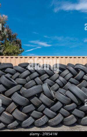 Molti pneumatici usati impilati all'esterno di un negozio di pneumatici. Foto Stock