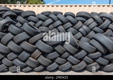 Molti pneumatici usati impilati all'esterno di un negozio di pneumatici. Foto Stock