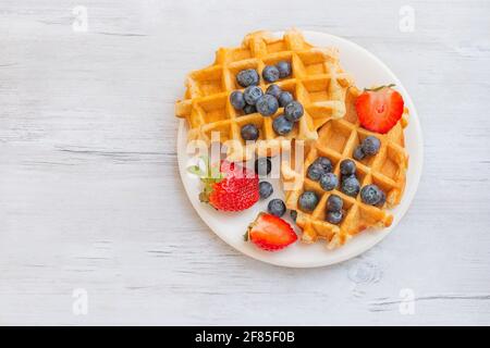 Waffle belgi fatti in casa con fragole e mirtilli. Deliziosa colazione con frutti di bosco. Foto Stock