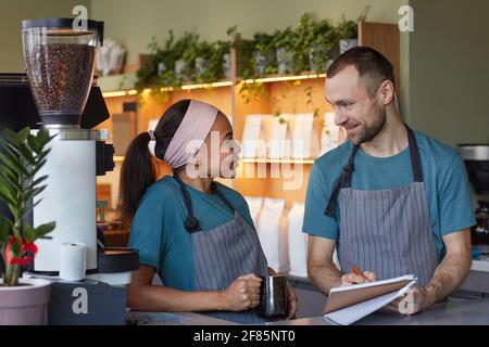 Vita in su ritratto di due baristi giovani sorridendo mentre godendo il lavoro nel caffè o nella caffetteria, copy space Foto Stock