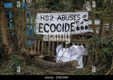 Wendover, Regno Unito. 9 aprile 2021. Una bandiera accusante HS2 Ltd di ecocida è appesa al campo di resistenza attivo di Wendover il 9 aprile 2021 a Wendover, Regno Unito. Il lavoro di abbattimento degli alberi per il progetto si sta svolgendo in diverse località tra Great Missenden e Wendover nell'AONB di Chilterns, anche di fronte al campo e a Jones Hill Wood. Credit: Mark Kerrison/Alamy Live News Foto Stock