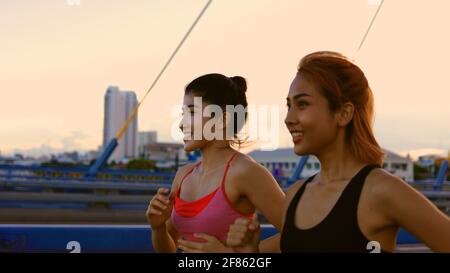 Due amici giovani sani e in forma che jogging in città strada durante la mattina presto mentre parla e sorridendo in città Foto Stock