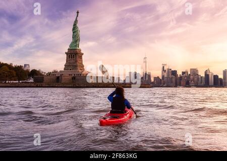 Avventuroso Woman Sea Kayaking vicino alla Statua della libertà Foto Stock
