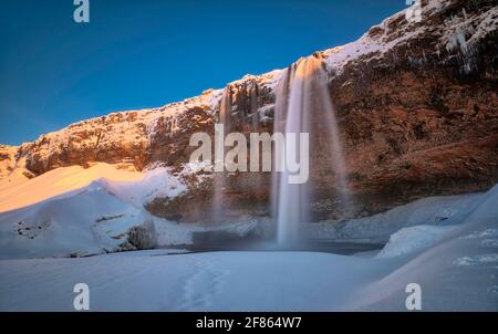 La caratteristica più distintiva di Seljalandsfoss è un sentiero che si estende intorno ad esso. Le scogliere dietro le cascate hanno un'ampia caverna, e rocce e. Foto Stock