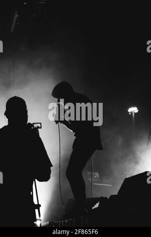 DUBAI, SUDAFRICA - 29 marzo 2021: rockstar sul palco con silhouette in bianco e nero e video fotografo con fotocamera davanti e crostata mano in mano Foto Stock