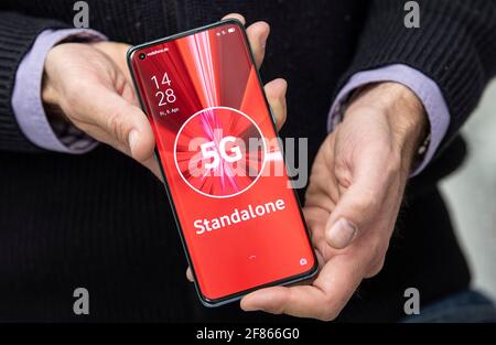 09 aprile 2021, Hessen, Francoforte sul meno: '5G Standalone' è scritto sul display di un telefono cellulare del produttore cinese 'Oppo', che un dipendente Vodafone mostra nella prima sede 'Standalone' a Francoforte. La tecnologia in questa sede non si basa più sul precedente standard LTE, ma si basa interamente sul 5G. L'ubicazione esatta della struttura non è pubblicata dall'azienda per motivi di sicurezza. (A dpa 'Vodafone inizia l'operazione dal vivo per la prossima fase di sviluppo del 5G' dal 12.04.2021) Foto: Boris Roessler/dpa Foto Stock