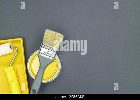 strumenti di pittura per lavori di ristrutturazione della casa - pennello, rullo con vassoio di vernice e lattina di vernice. ultimo sfondo grigio. Foto Stock