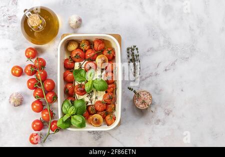 Formaggio feta al forno con pomodori, capperi, aglio, erbe e olio d'oliva. Nel forno si trasforma in una salsa stupefacente da solo. Basta aggiungere un po 'di cotto passato Foto Stock