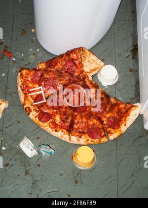 La vecchia pizza mangiata a metà ha lasciato sopra dopo una festa selvaggia in una casa disordinata, scattata in stile flash-on-camera. Foto Stock