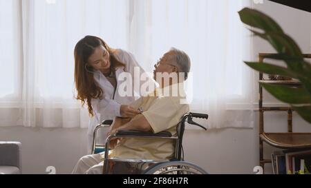 La donna infermiera medico indossa un cardiologo bianco uniforme che esamina il paziente anziano o anziano anziano durante la seduta su sedia a rotelle che ascolta il controllo battito cardiaco Foto Stock