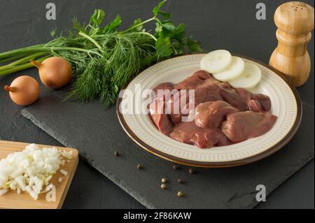 Fegato di pollo crudo in ciotola su sfondo nero. Ingredienti per cucinare. Foto Stock