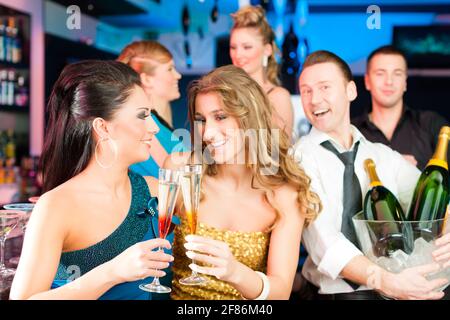 I giovani nel club o al bar a bere champagne e divertirsi Foto Stock