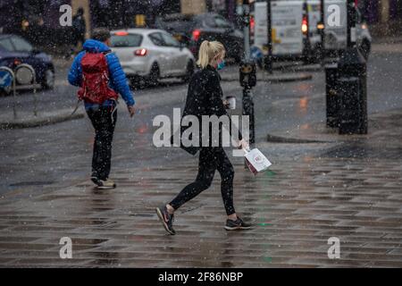 Londra, Regno Unito. Aprile 12 2021: I pendolari fanno il loro modo di lavorare attraverso una sorprendente neve di primavera Blizzard a Wimbledon il primo giorno le restrizioni del coronavirus sono revocate in Inghilterra per consentire alle persone di ottenere il loro taglio di capelli e mangiare e bere fuori pub e ristoranti. 12 Aprile, Wimbledon, Southwest London SW19, Inghilterra, UK Credit: Jeff Gilbert/Alamy Live News Foto Stock