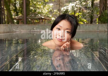 Ritratto bella giovane donna immergersi in piscina al tranquillo Onsen Foto Stock