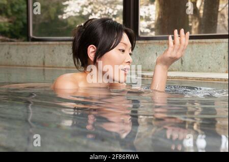 Giovane donna che si immerse in acqua al centro benessere Onsen Foto Stock