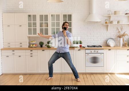 Uomo divertente che canta in utensili da cucina, balla, divertirsi in cucina Foto Stock