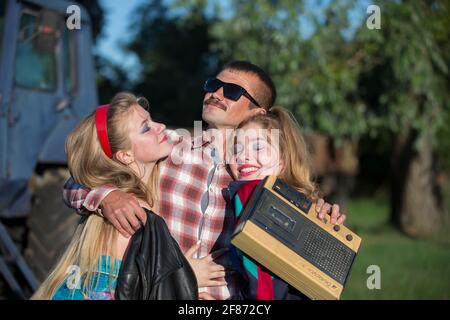 Uomo divertente con registratore di cassette abbraccia le ragazze. Persone nello stile degli anni novanta. Foto Stock