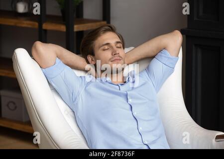 Primo piano con le mani dietro la testa appoggiate in poltrona Foto Stock