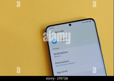 New york, USA - 12 aprile 2021: Modifica dell'impostazione della privacy nell'applicazione twitter sullo schermo dello smartphone su sfondo giallo Foto Stock