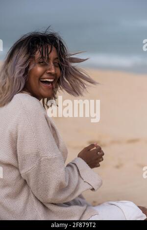 Ritratto di donna felice seduta sulla sabbia in spiaggia Foto Stock