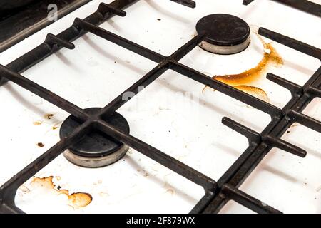 Stufa a gas sporca e bruciatori dopo la cottura a casa in cucina, primo piano. Foto Stock